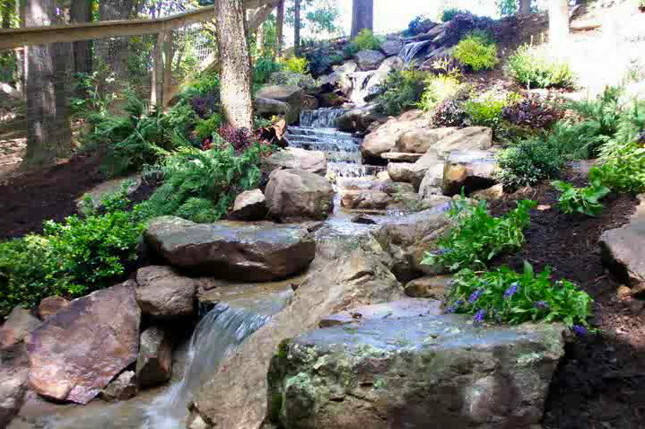 This is an example of a mid-sized shade backyard stone water fountain landscape.