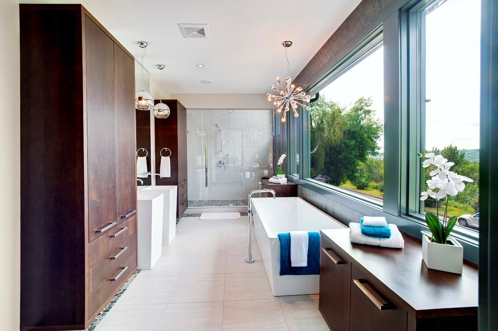 This is an example of a contemporary bathroom in Calgary with a pedestal sink, flat-panel cabinets, dark wood cabinets, a freestanding tub, an alcove shower and beige tile.