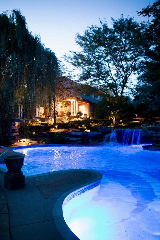 Inspiration for an expansive transitional backyard custom-shaped pool in Other with with a pool and stamped concrete.