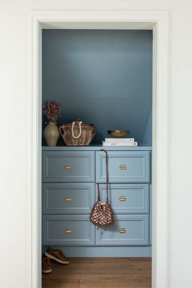 Kleines Ankleidezimmer mit Einbauschrank, blauen Schränken und braunem Holzboden in Orange County
