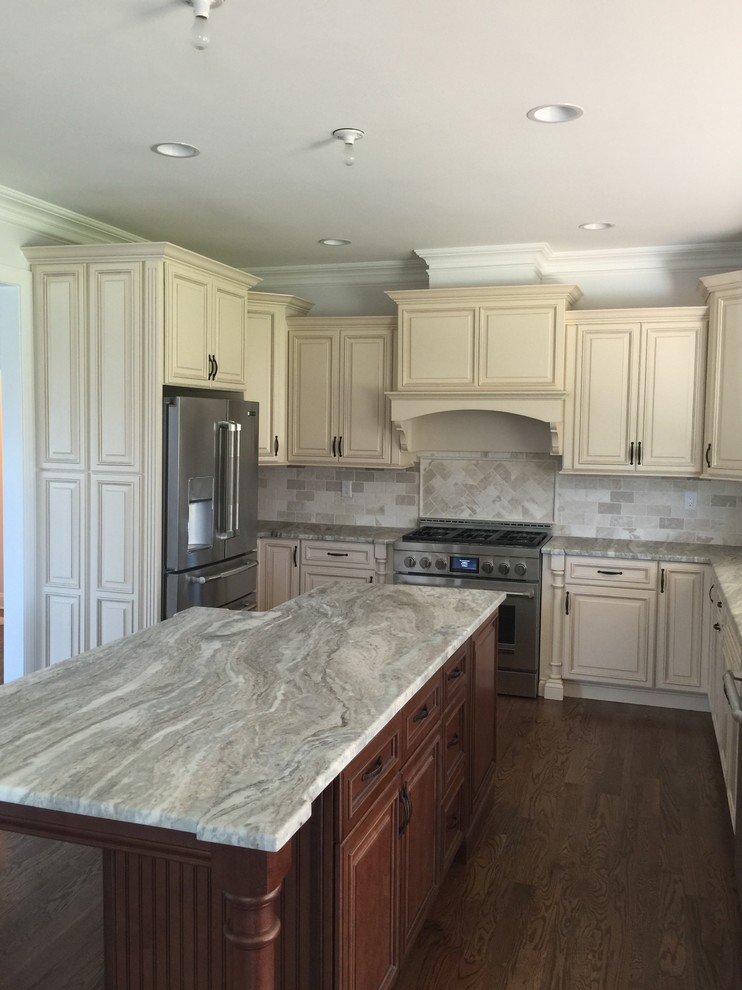 Large transitional l-shaped separate kitchen in New York with an undermount sink, raised-panel cabinets, white cabinets, granite benchtops, grey splashback, stone tile splashback, stainless steel appliances, dark hardwood floors, with island and brown floor.
