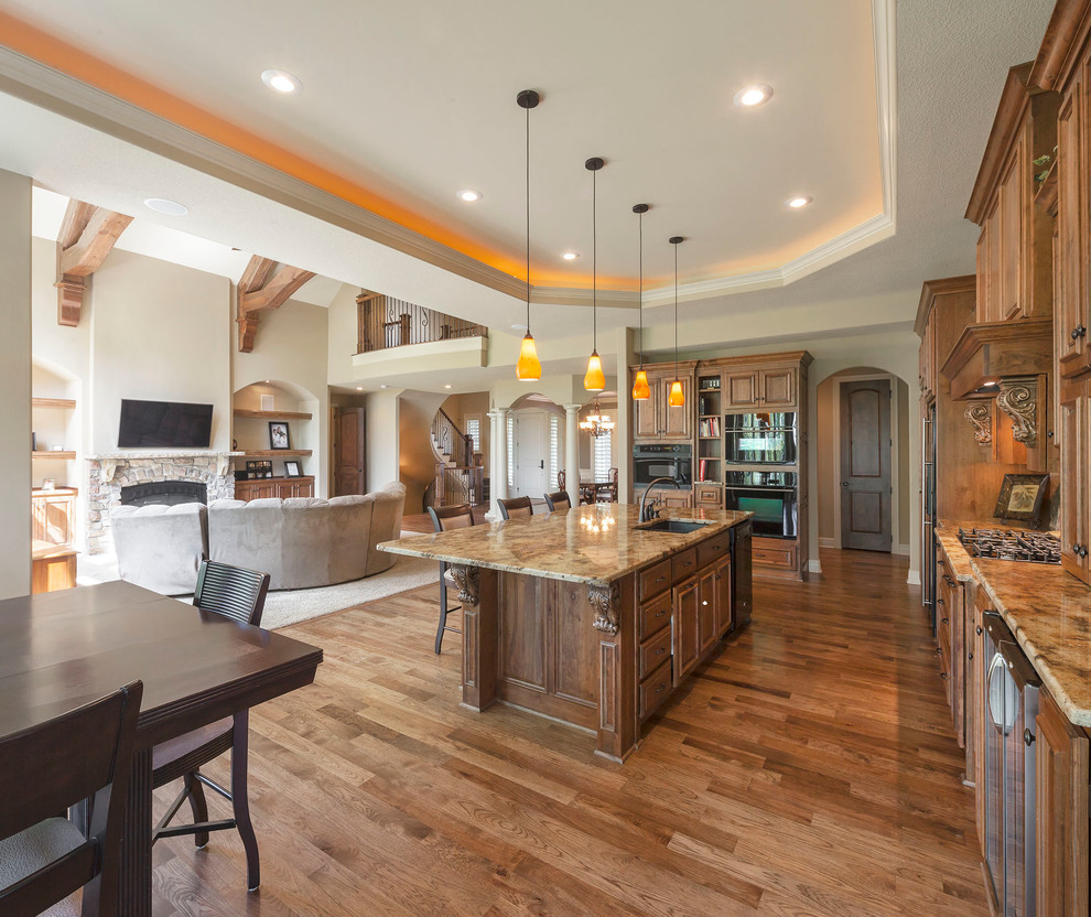 Inspiration for an expansive traditional galley open plan kitchen in Kansas City with an undermount sink, raised-panel cabinets, dark wood cabinets, granite benchtops, stainless steel appliances and with island.