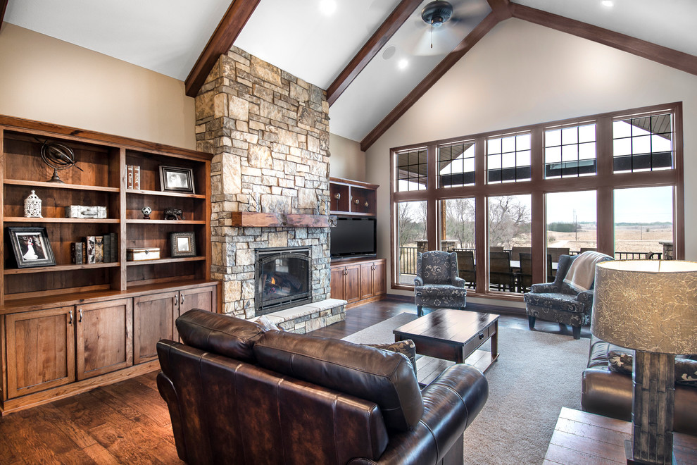 Photo of an arts and crafts open concept family room in Omaha with beige walls, dark hardwood floors, a standard fireplace and a stone fireplace surround.