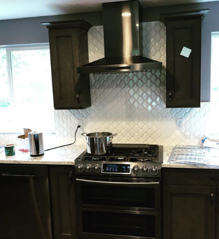 Example of a mid-sized transitional light wood floor and brown floor kitchen design in Seattle with an undermount sink, flat-panel cabinets, brown cabinets, quartz countertops, white backsplash, mosaic tile backsplash, stainless steel appliances and white countertops