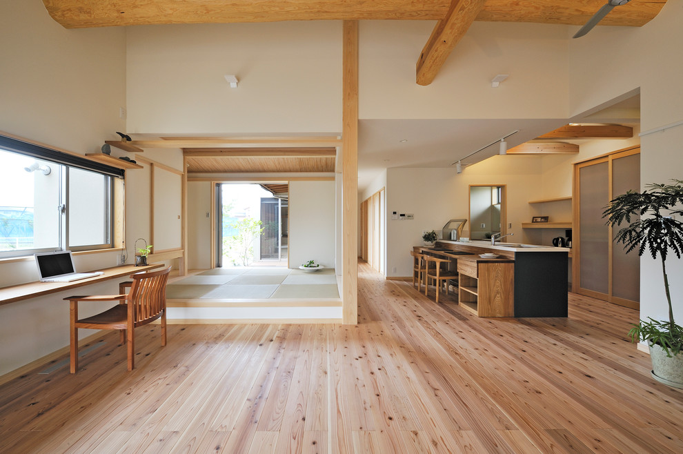 Photo of an asian open concept living room in Other with beige walls, light hardwood floors, a wall-mounted tv and beige floor.