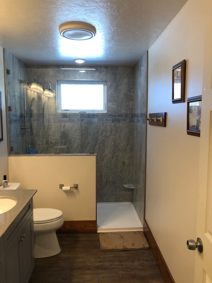 Inredning av ett amerikanskt mellanstort grå grått en-suite badrum, med luckor med profilerade fronter, blå skåp, en öppen dusch, en toalettstol med separat cisternkåpa, grå kakel, porslinskakel, vita väggar, vinylgolv, ett integrerad handfat, bänkskiva i onyx, flerfärgat golv och med dusch som är öppen