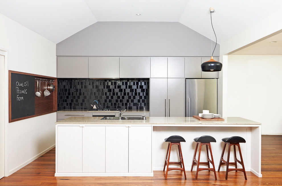 This is an example of a contemporary galley kitchen in Brisbane with a drop-in sink, black splashback, stainless steel appliances and flat-panel cabinets.