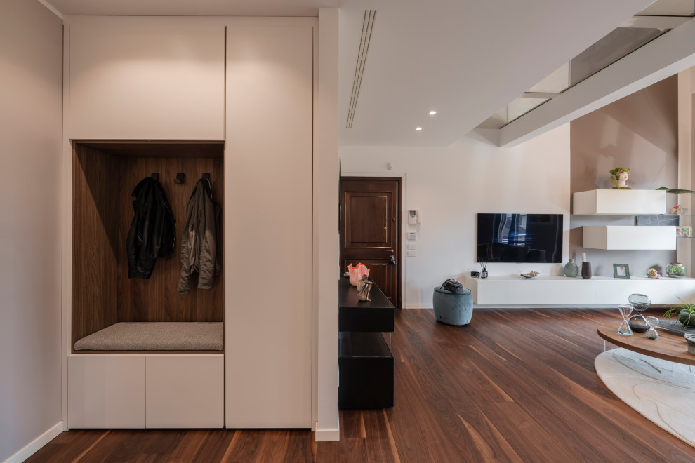 Inspiration for a large modern foyer in Milan with white walls, dark hardwood flooring, a single front door, a brown front door, brown floors and a drop ceiling.