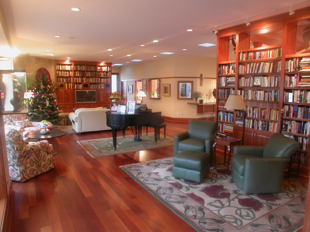 Photo of an expansive arts and crafts open concept living room in Raleigh with a library, beige walls, medium hardwood floors, a corner fireplace, a stone fireplace surround and a built-in media wall.