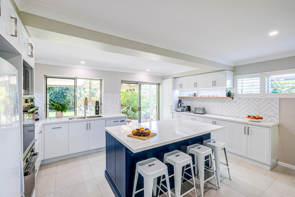 Inspiration for a large contemporary u-shaped kitchen pantry in Brisbane with a double-bowl sink, shaker cabinets, blue cabinets, quartz benchtops, white splashback, subway tile splashback, stainless steel appliances, ceramic floors, with island, beige floor and white benchtop.