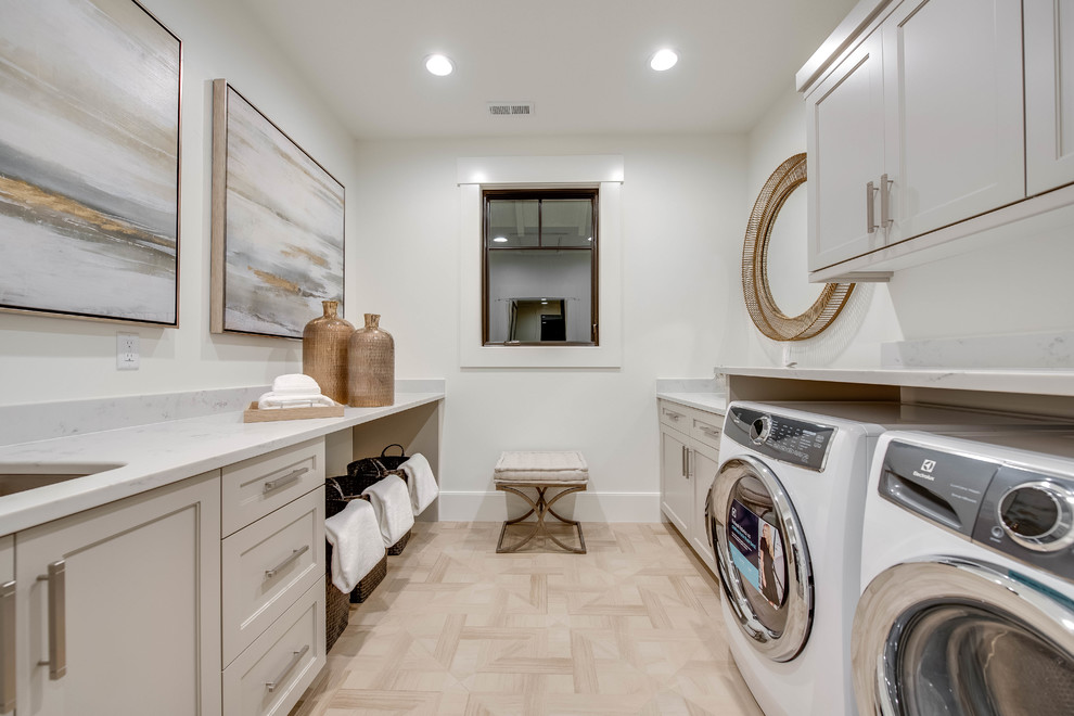 This is an example of a country galley dedicated laundry room in Other with an undermount sink, recessed-panel cabinets, grey cabinets, light hardwood floors, a side-by-side washer and dryer, beige floor, grey benchtop and white walls.