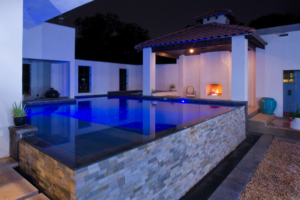 This is an example of a small contemporary courtyard custom-shaped infinity pool in Austin with a water feature and concrete slab.