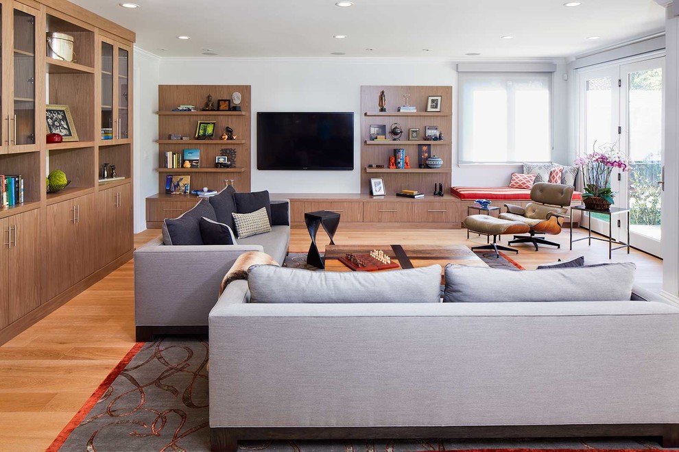 Photo of a mid-sized contemporary open concept family room in San Francisco with white walls, medium hardwood floors and a wall-mounted tv.