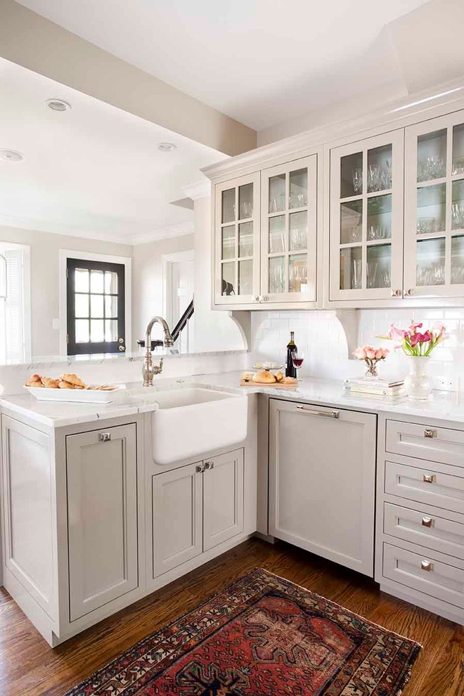 Example of a small classic medium tone wood floor enclosed kitchen design in Atlanta with glass-front cabinets, subway tile backsplash, a farmhouse sink, gray cabinets, marble countertops, white backsplash, paneled appliances and no island