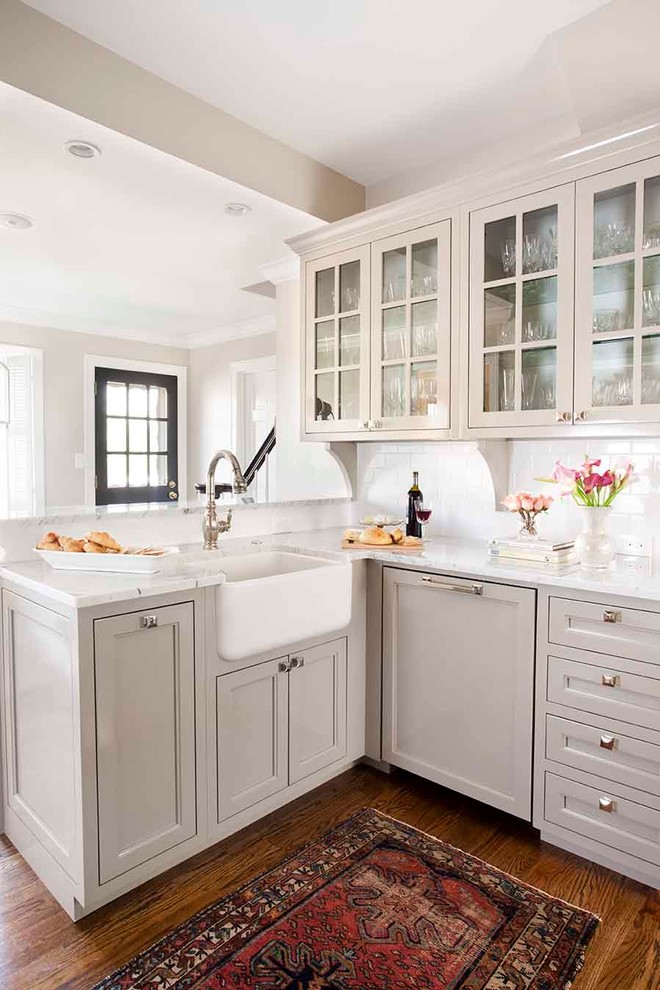 Photo of a small traditional kitchen in Atlanta with glass-front cabinets, subway tile splashback, a farmhouse sink, grey cabinets, marble benchtops, white splashback, panelled appliances, medium hardwood floors and a peninsula.
