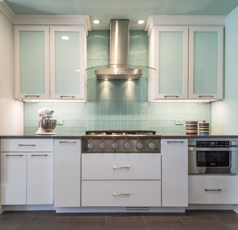 Transitional porcelain tile kitchen photo with flat-panel cabinets, white cabinets, granite countertops, blue backsplash, glass tile backsplash and stainless steel appliances
