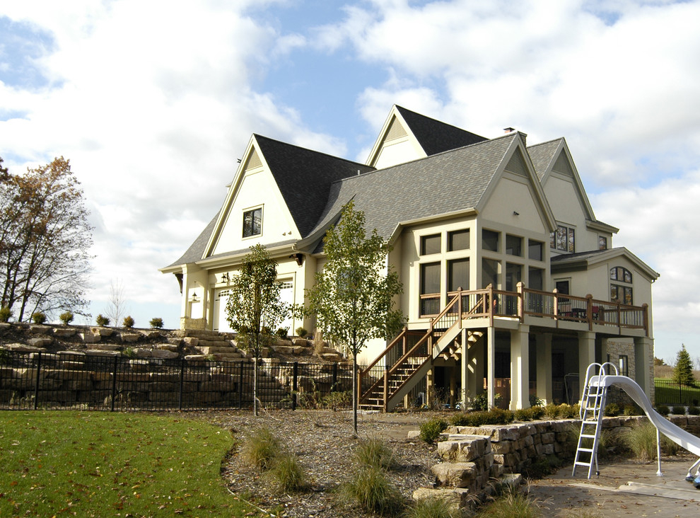 Photo of a country two-storey stucco beige house exterior in Grand Rapids with a gable roof and a shingle roof.