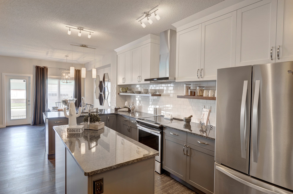 Inspiration for a mid-sized transitional l-shaped vinyl floor and black floor eat-in kitchen remodel in Edmonton with an undermount sink, shaker cabinets, gray cabinets, granite countertops, white backsplash, subway tile backsplash, stainless steel appliances and an island
