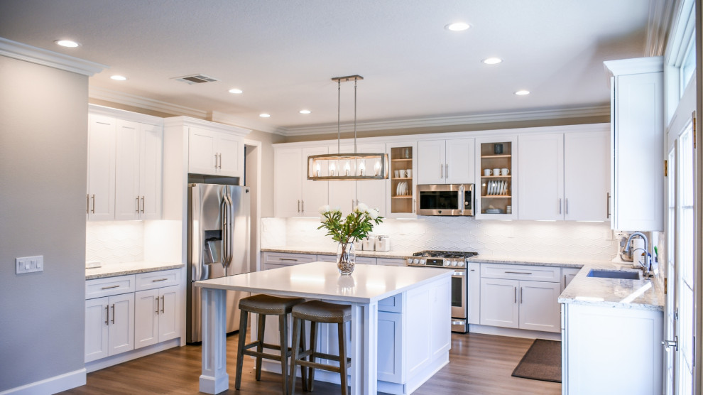 A modern kitchen with white cabinets and stainless steel appliances, designed with open layout and stylish finishes.