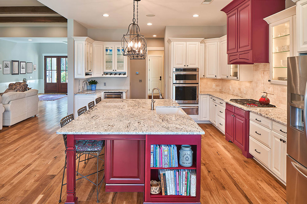 Inspiration for a traditional l-shaped open plan kitchen in Atlanta with a farmhouse sink, raised-panel cabinets, red cabinets, granite benchtops, beige splashback, stone tile splashback, stainless steel appliances, medium hardwood floors and with island.