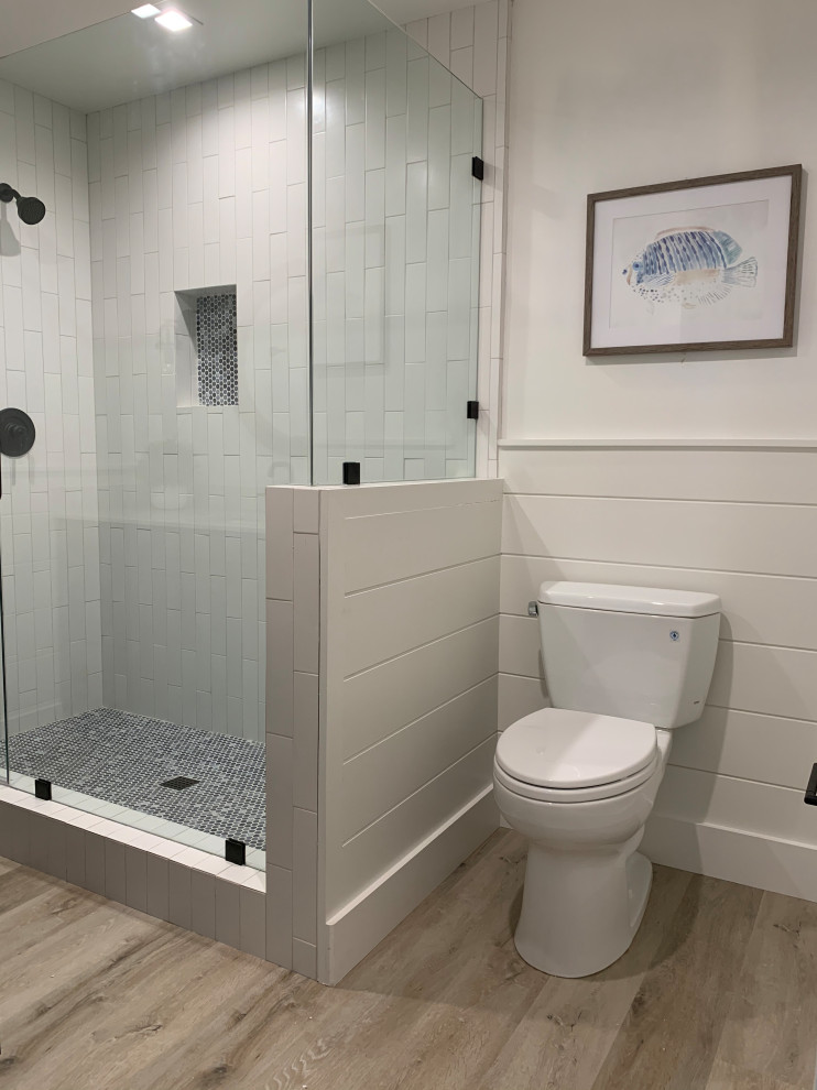 Bild på ett litet maritimt vit vitt badrum med dusch, med skåp i shakerstil, blå skåp, en toalettstol med separat cisternkåpa, vit kakel, keramikplattor, blå väggar, vinylgolv, ett undermonterad handfat, bänkskiva i kvarts och beiget golv