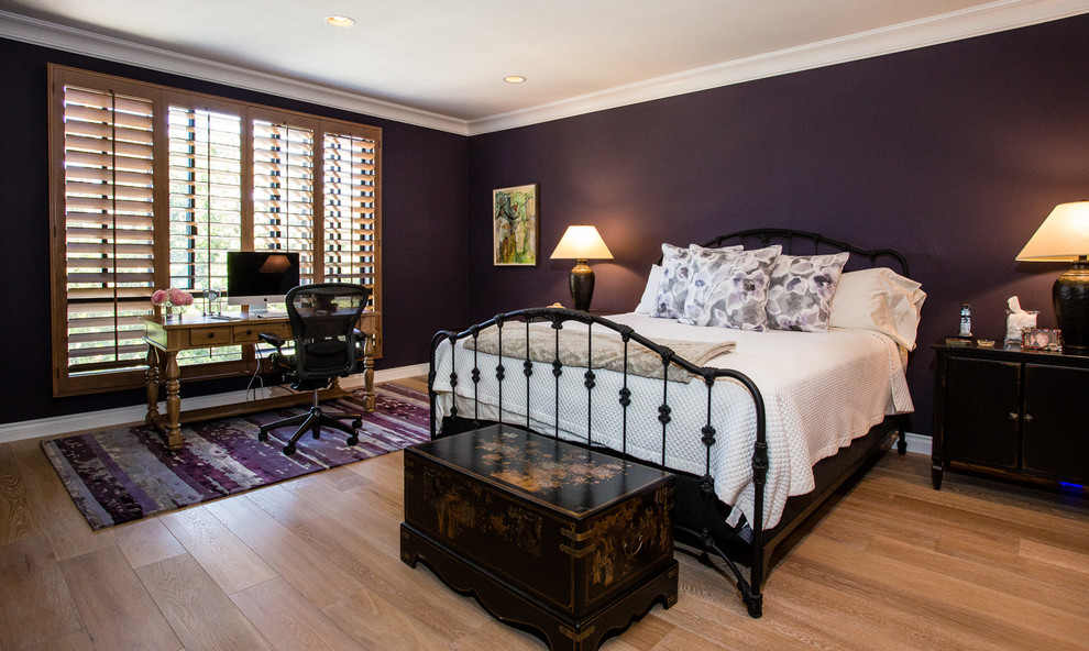 This is an example of a large traditional master bedroom in Los Angeles with purple walls, light hardwood floors, no fireplace and brown floor.