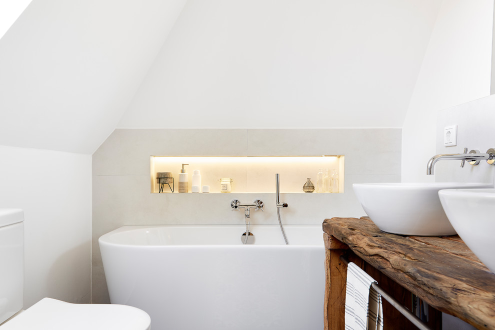 Diseño de cuarto de baño principal de estilo de casa de campo con sanitario de una pieza, baldosas y/o azulejos blancos, paredes blancas, lavabo sobreencimera, encimera de madera, suelo negro y encimeras marrones