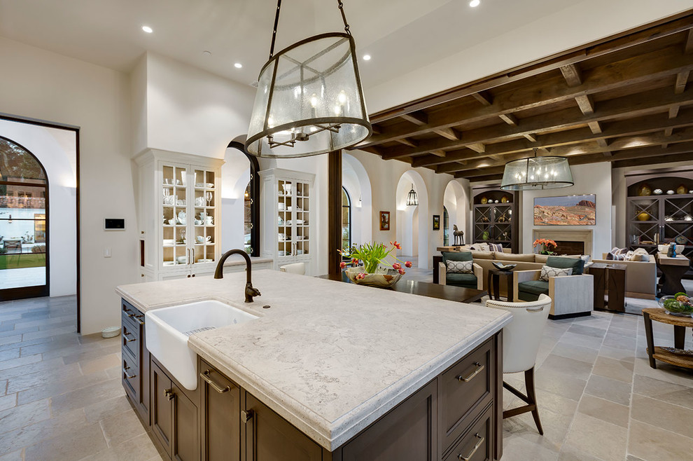 Inspiration for an expansive mediterranean l-shaped open plan kitchen in Other with a farmhouse sink, raised-panel cabinets, dark wood cabinets, limestone benchtops, limestone floors, with island, grey floor and grey benchtop.