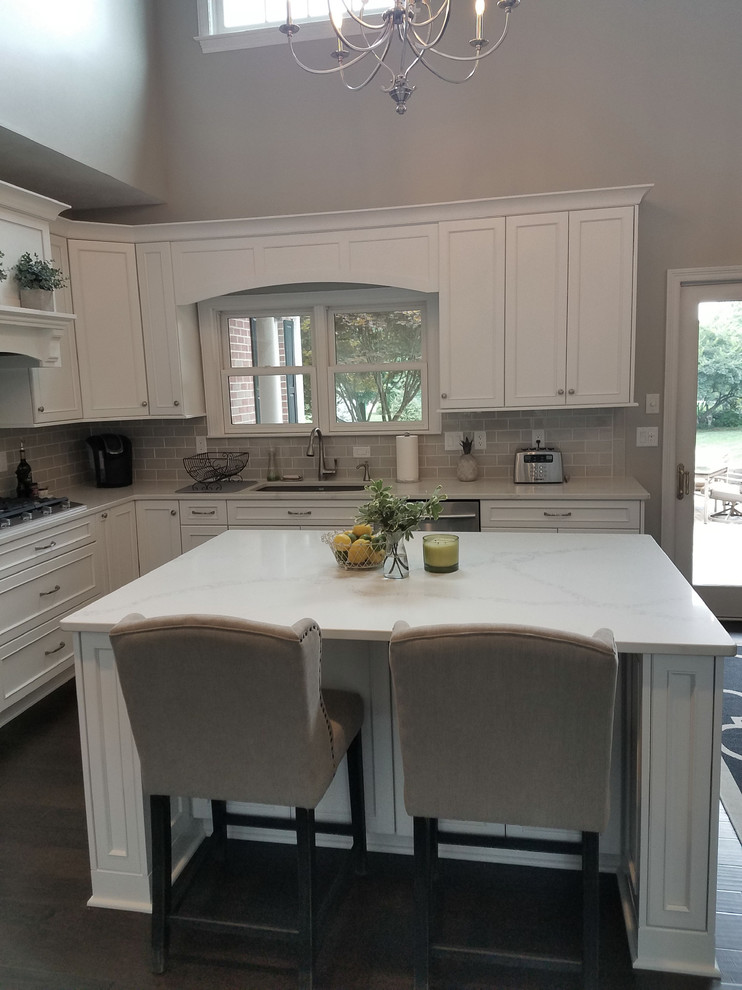 This is an example of a mid-sized transitional l-shaped eat-in kitchen in Other with an undermount sink, flat-panel cabinets, white cabinets, quartz benchtops, grey splashback, ceramic splashback, stainless steel appliances, with island and white benchtop.