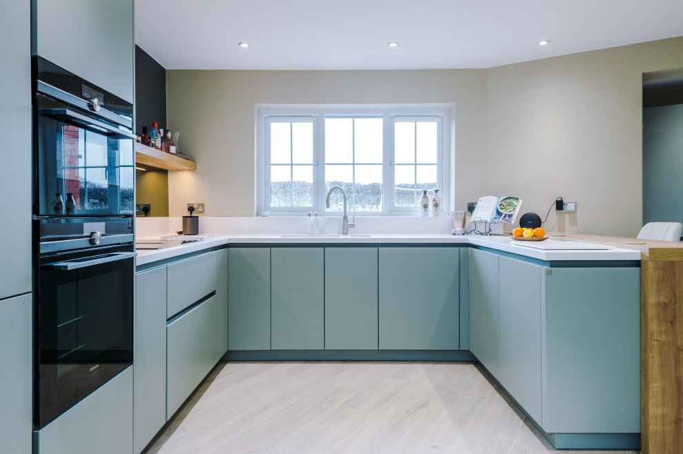Mittelgroße Moderne Küche in U-Form mit Einbauwaschbecken, blauen Schränken und Porzellan-Bodenfliesen in Manchester