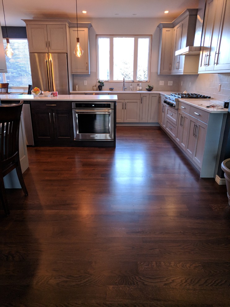 Large transitional l-shaped dark wood floor and brown floor eat-in kitchen photo in Denver with an undermount sink, shaker cabinets, gray cabinets, quartz countertops, white backsplash, subway tile backsplash, stainless steel appliances and an island