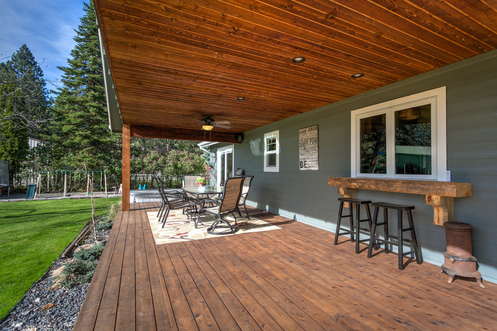 Mid-sized mountain style backyard deck photo in Seattle with a roof extension