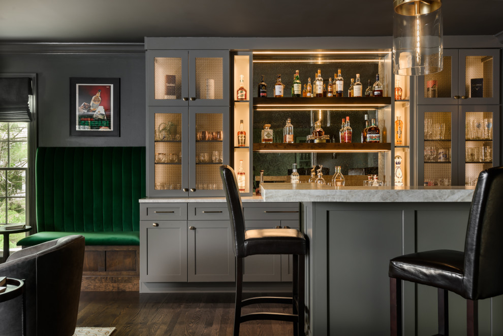 This is an example of a transitional home bar in St Louis with shaker cabinets, green splashback, subway tile splashback and brown floor.