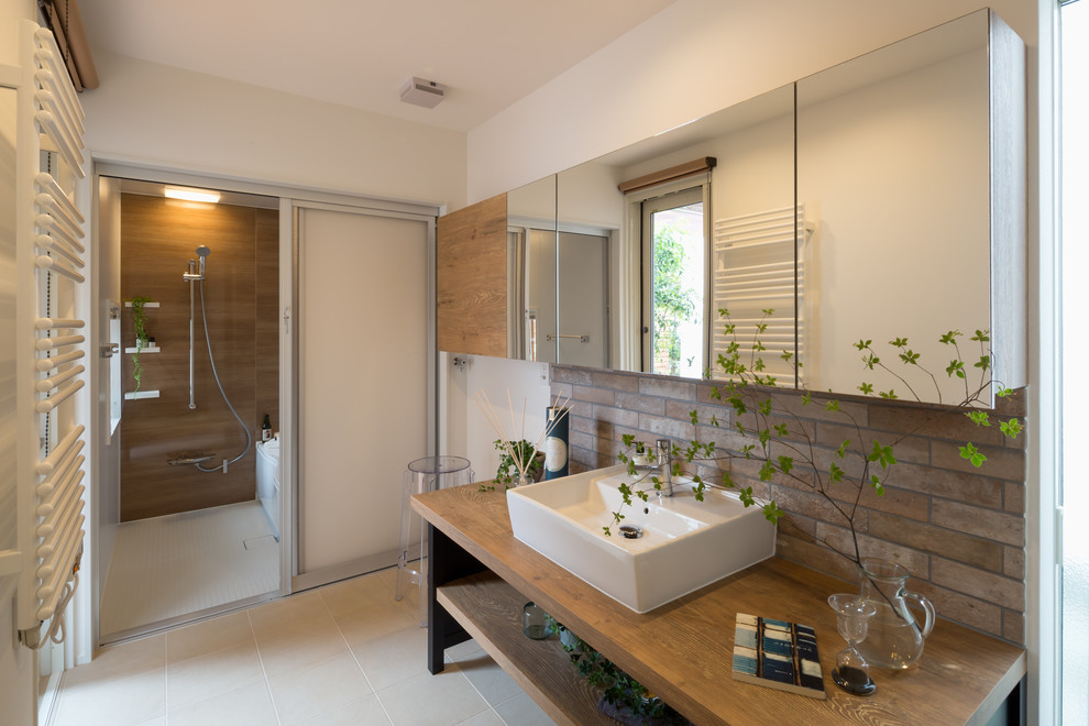 This is an example of an asian bathroom in Other with open cabinets, white walls, a vessel sink, wood benchtops, beige floor and brown benchtops.