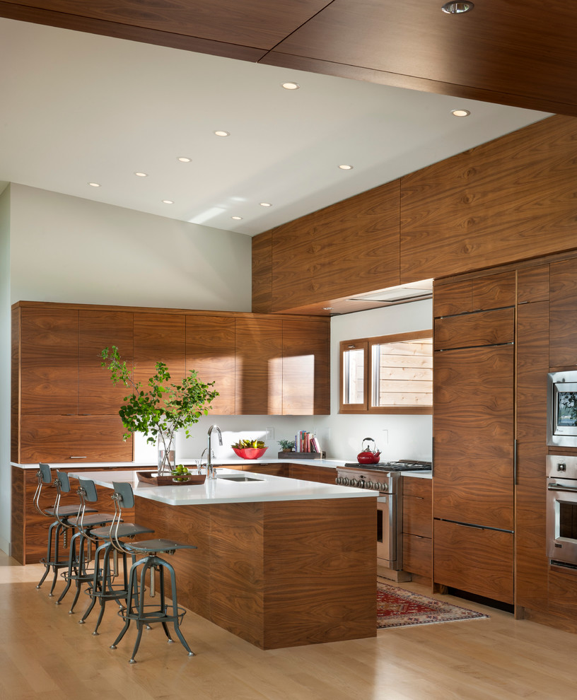This is an example of a contemporary l-shaped kitchen in Other with an undermount sink, flat-panel cabinets, medium wood cabinets, panelled appliances, light hardwood floors and with island.