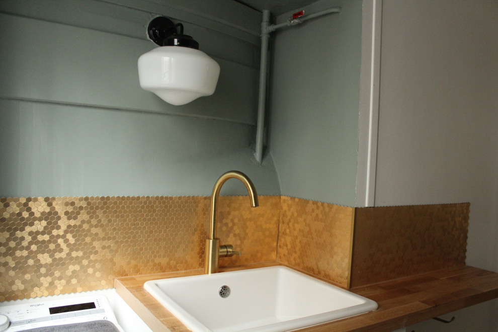 This is an example of a small midcentury galley dedicated laundry room in Paris with an undermount sink, flat-panel cabinets, green cabinets, laminate benchtops, metal splashback, green walls, multi-coloured floor and brown benchtop.
