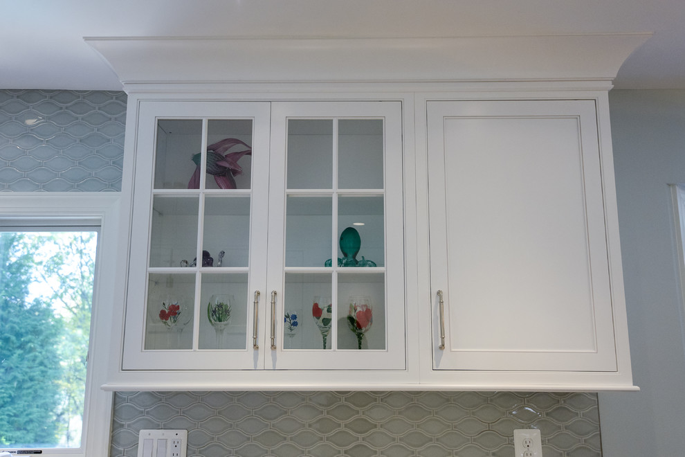 Eat-in kitchen - large transitional u-shaped eat-in kitchen idea in DC Metro with white cabinets, an island, glass-front cabinets, gray backsplash and porcelain backsplash