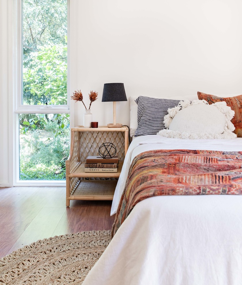 Photo of a beach style bedroom in Wollongong with white walls, medium hardwood floors and brown floor.