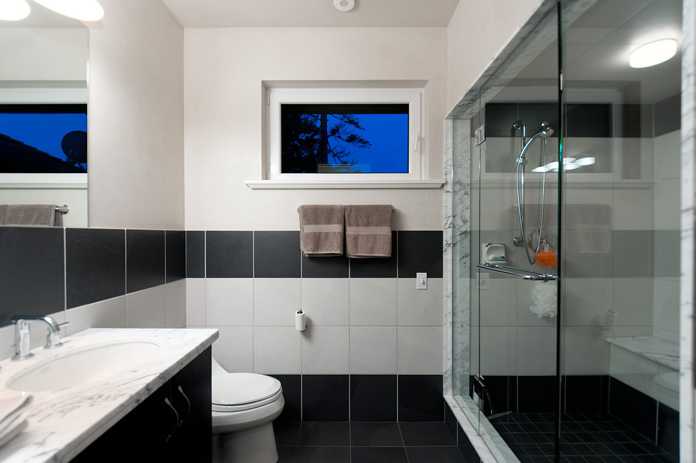 Design ideas for a mid-sized contemporary 3/4 bathroom in Vancouver with flat-panel cabinets, black cabinets, an alcove shower, a one-piece toilet, black tile, white tile, porcelain tile, white walls, porcelain floors, an undermount sink and marble benchtops.