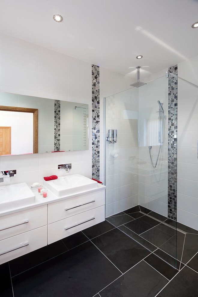 Photo of a mid-sized modern master bathroom in Cornwall with flat-panel cabinets, white cabinets, an open shower, white tile, ceramic tile, white walls, ceramic floors, a console sink, black floor and an open shower.