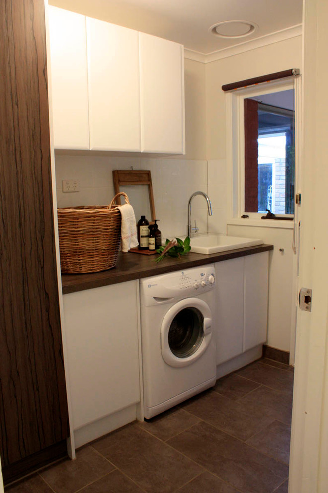 Inspiration for a mid-sized transitional single-wall utility room in Melbourne with a farmhouse sink, white cabinets, laminate benchtops, white walls and ceramic floors.