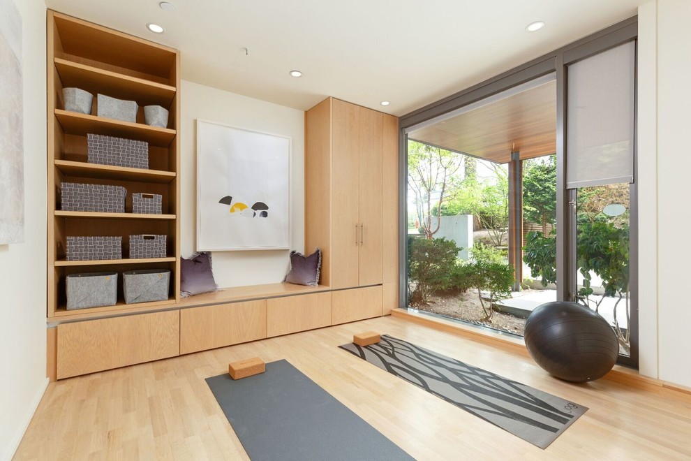 Photo of a contemporary home yoga studio in Vancouver with white walls, light hardwood floors and beige floor.