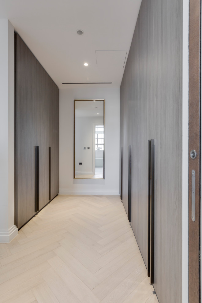 Medium sized contemporary gender neutral walk-in wardrobe in London with flat-panel cabinets and medium wood cabinets.