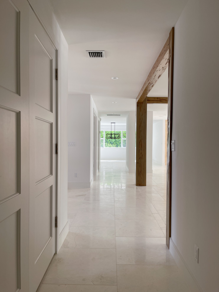 Mid-sized beach style entry hall in Miami with white walls, marble floors, beige floor and exposed beam.
