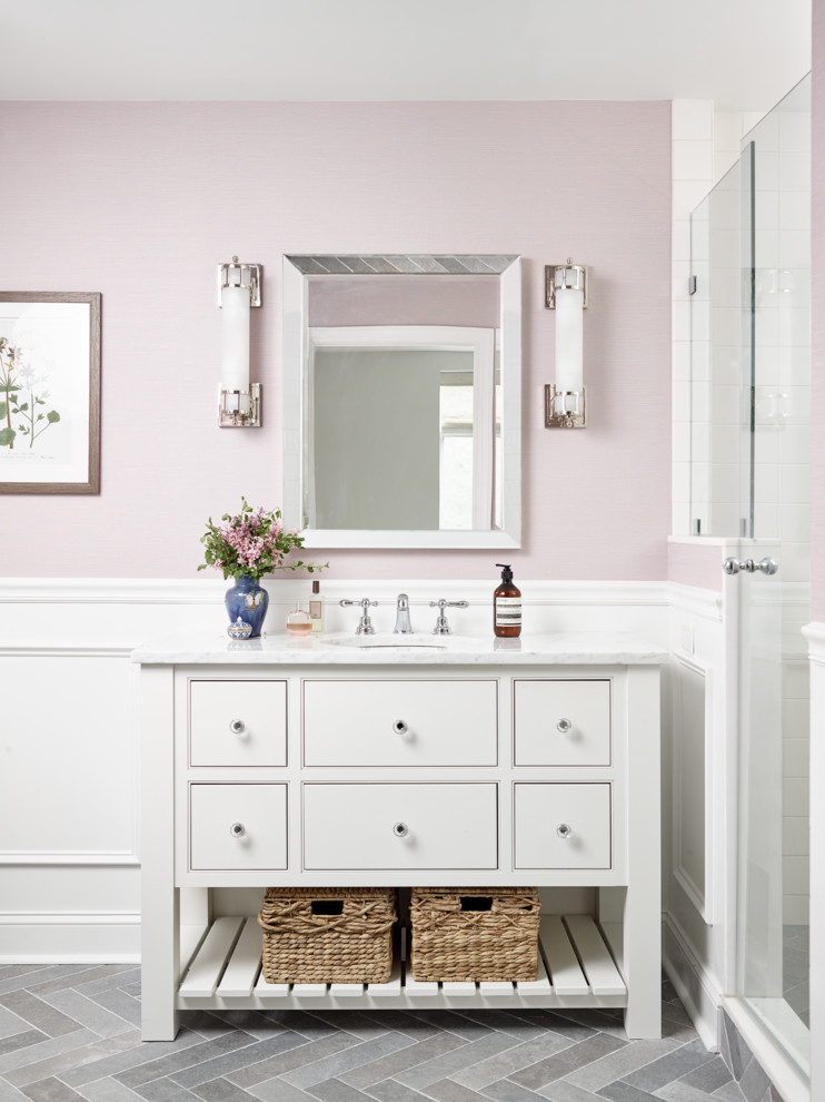 This is an example of a mid-sized transitional master bathroom in Philadelphia with white cabinets, ceramic floors, marble benchtops, grey floor, a hinged shower door, white benchtops, an alcove shower, white tile, pink walls, an undermount sink and beaded inset cabinets.