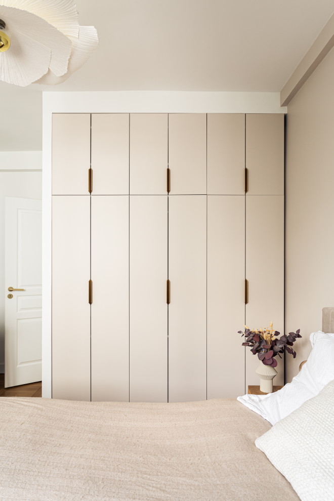 Modelo de armario y vestidor unisex moderno de tamaño medio con a medida, armarios con rebordes decorativos, puertas de armario beige y suelo de madera clara