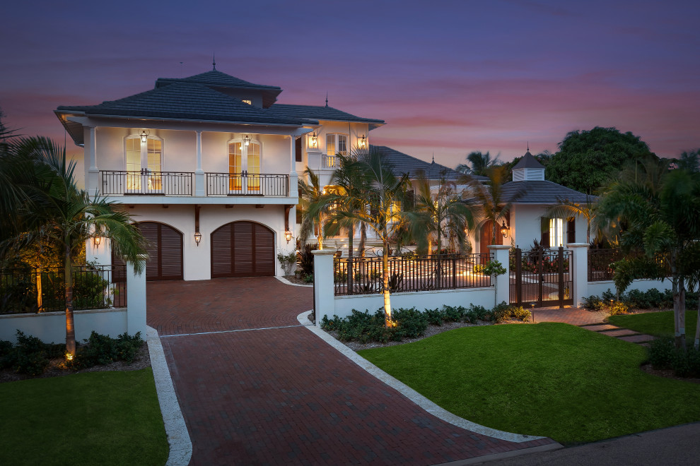 Inspiration for a large beach style two-storey stucco beige house exterior in Tampa with a gable roof and a shingle roof.