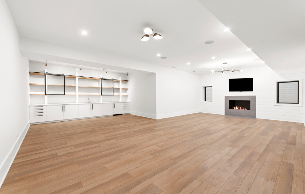 Inspiration for a large transitional underground vinyl floor and brown floor basement remodel in Chicago with a bar, white walls, a standard fireplace and a stone fireplace