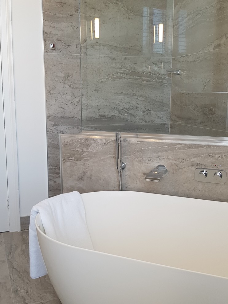 This is an example of a large contemporary bathroom in Other with flat-panel cabinets, white cabinets, a freestanding bath, a wall mounted toilet, grey tiles, porcelain tiles, grey walls, porcelain flooring, a wall-mounted sink, marble worktops, grey floors, an open shower and white worktops.