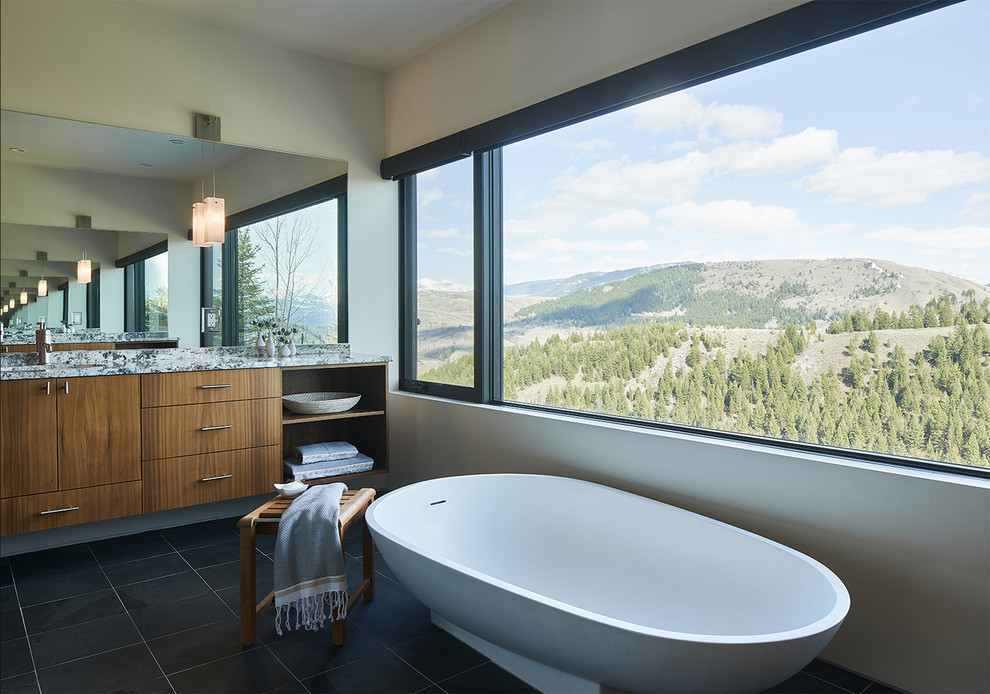 Inspiration for a contemporary master bathroom in Other with flat-panel cabinets, dark wood cabinets, a freestanding tub, grey walls, black floor and grey benchtops.